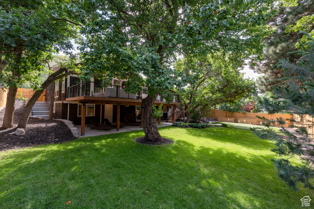 View of yard with stairs, a wooden deck, and a patio area