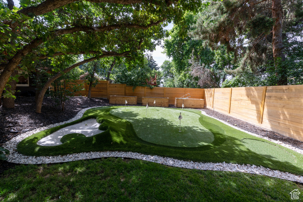 Fenced backyard featuring a putting area