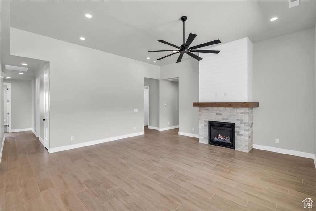 Unfurnished living room featuring a ceiling fan, wood finished floors, a large fireplace, and recessed lighting