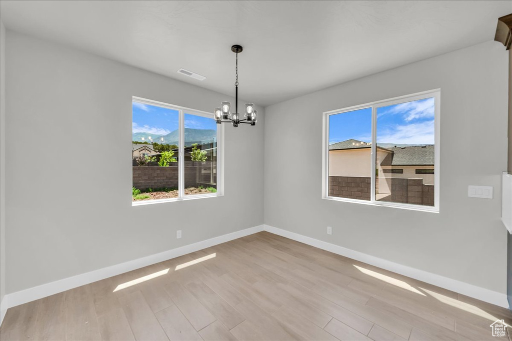 Unfurnished room featuring a chandelier and wood finished floors