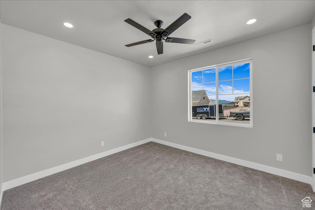 Empty room featuring a ceiling fan, recessed lighting, and dark carpet