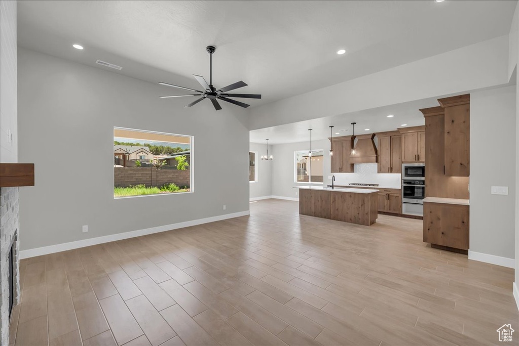 Unfurnished living room featuring a ceiling fan, recessed lighting, light wood-type flooring, and a fireplace