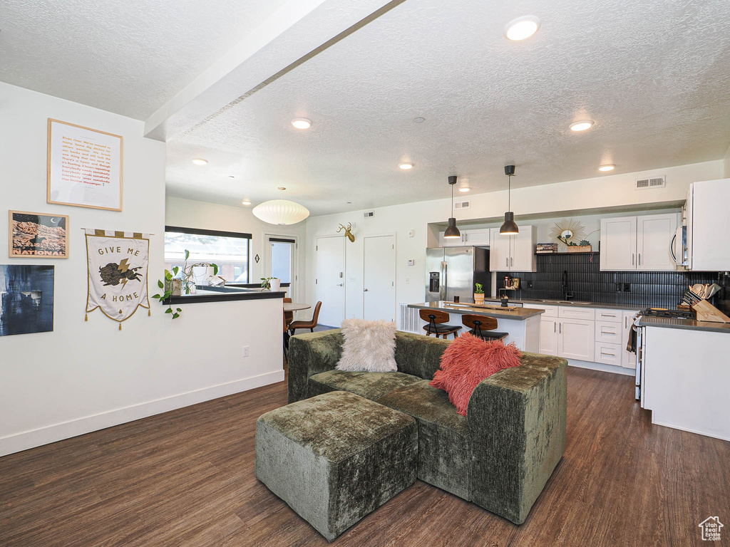 Living area featuring dark wood-style floors, a textured ceiling, and recessed lighting