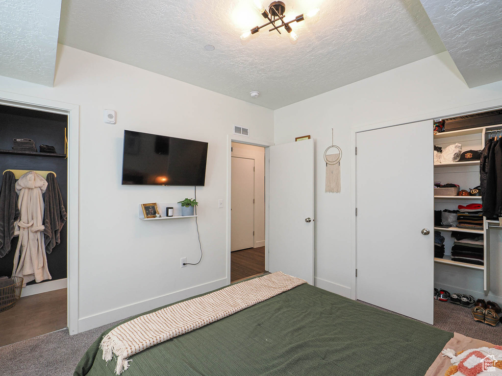 Bedroom with a textured ceiling, a closet, carpet flooring, and a walk in closet