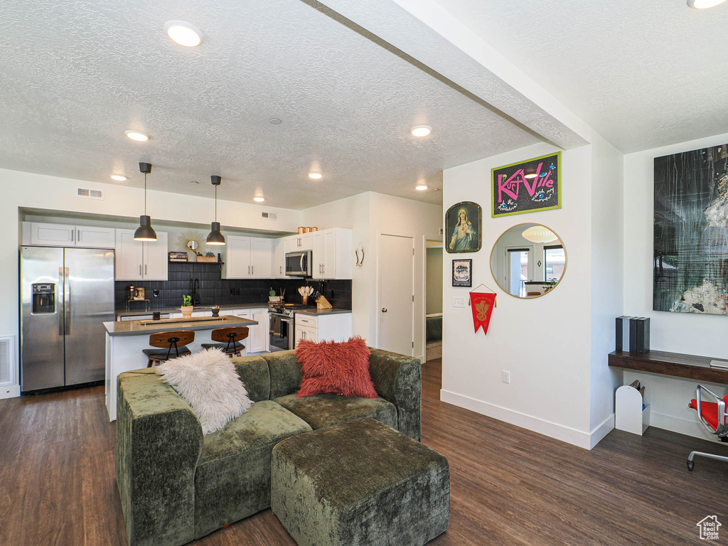 Living room with a textured ceiling, dark wood-style floors, and recessed lighting