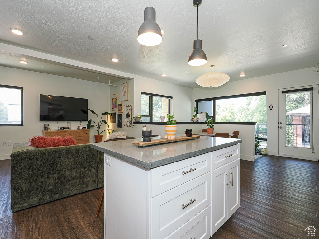 Kitchen featuring open floor plan, recessed lighting, dark wood-type flooring, a textured ceiling, and a center island