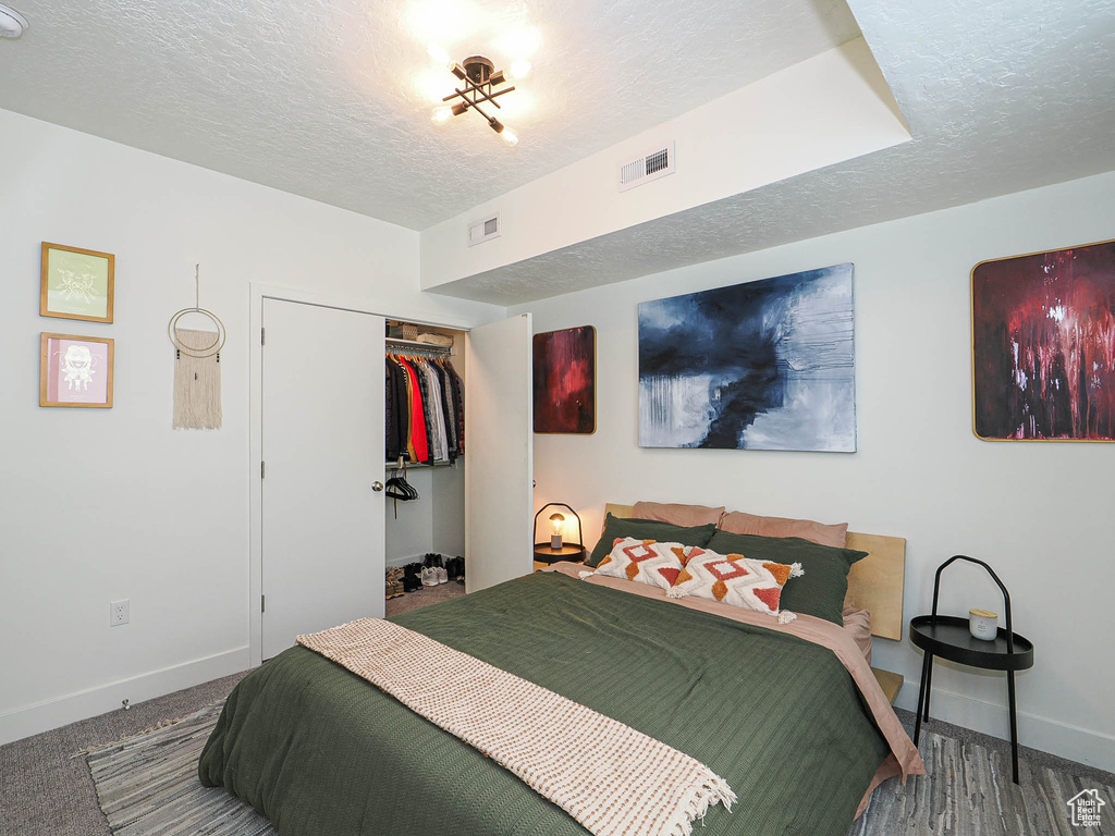 Bedroom with a textured ceiling, a closet, and carpet flooring