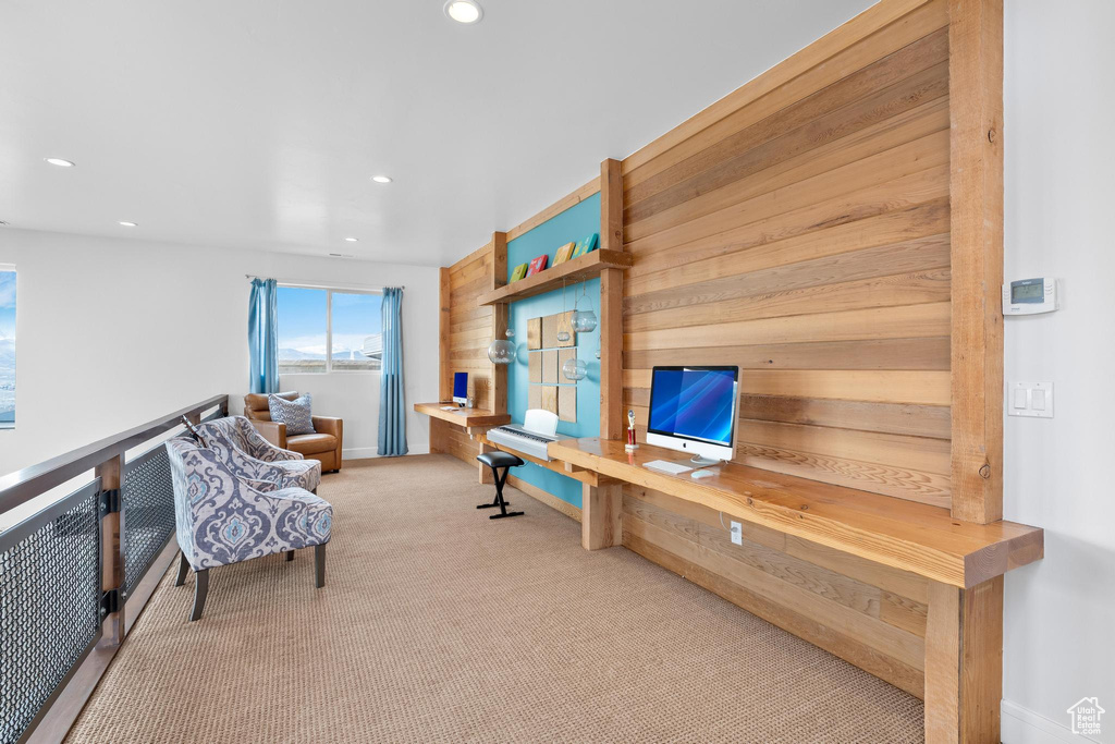 Office space featuring built in desk, recessed lighting, carpet, and wood walls
