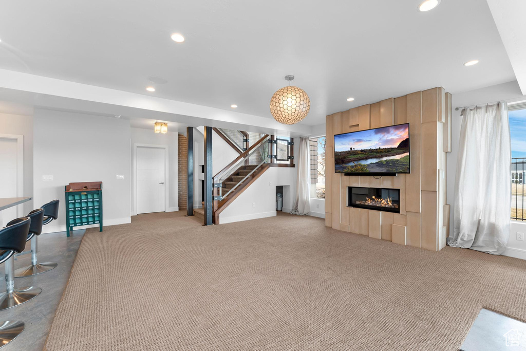Carpeted living room with recessed lighting, stairway, and a large fireplace