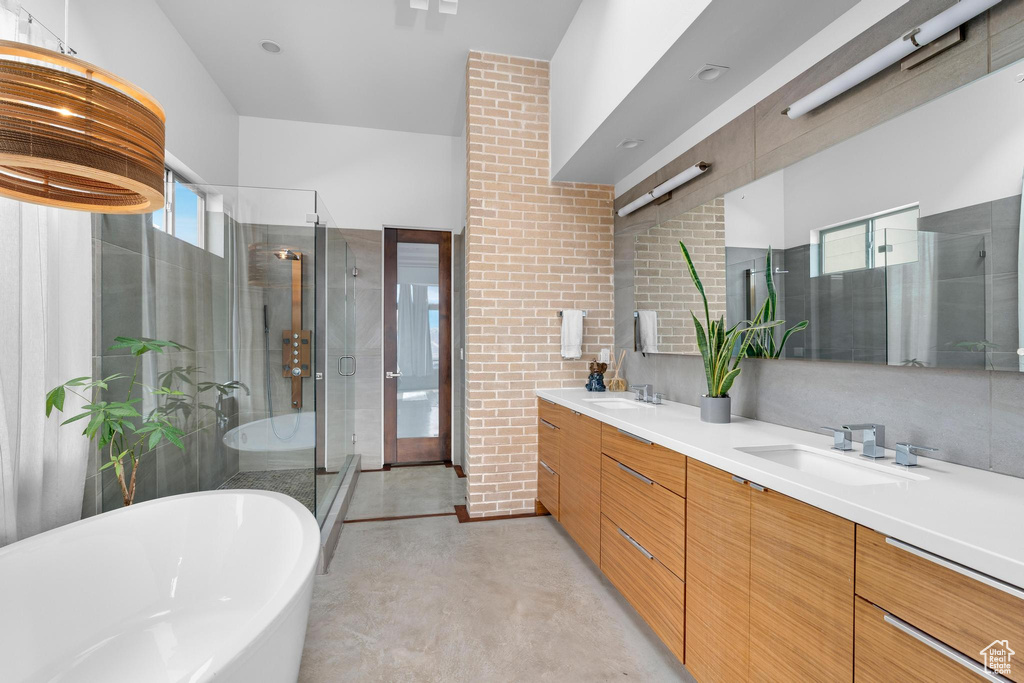 Full bath with concrete flooring, a freestanding bath, double vanity, and a stall shower