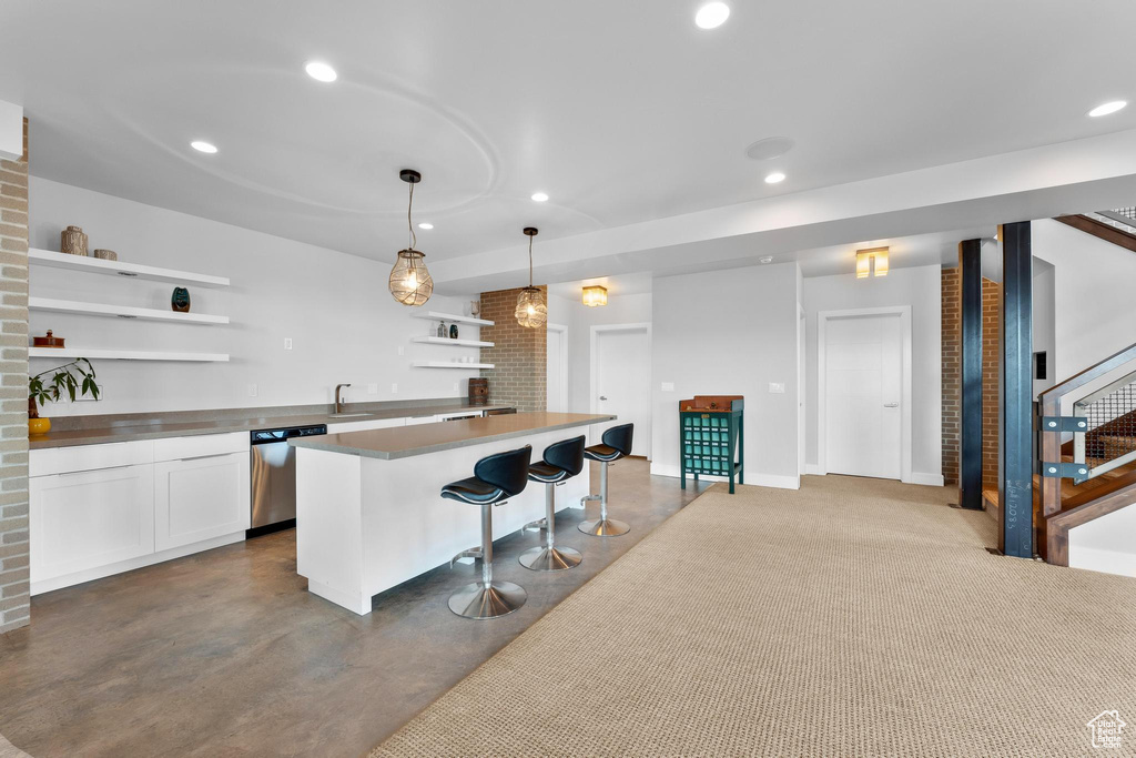 Kitchen with open shelves, stainless steel dishwasher, a kitchen bar, white cabinetry, and finished concrete flooring