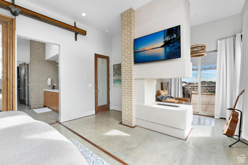 Bedroom featuring access to outside, concrete flooring, and ensuite bathroom