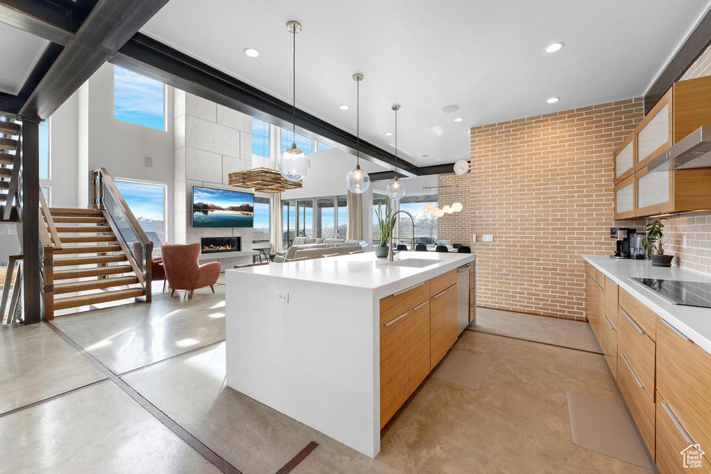 Kitchen featuring modern cabinets, black electric cooktop, concrete flooring, light countertops, and recessed lighting