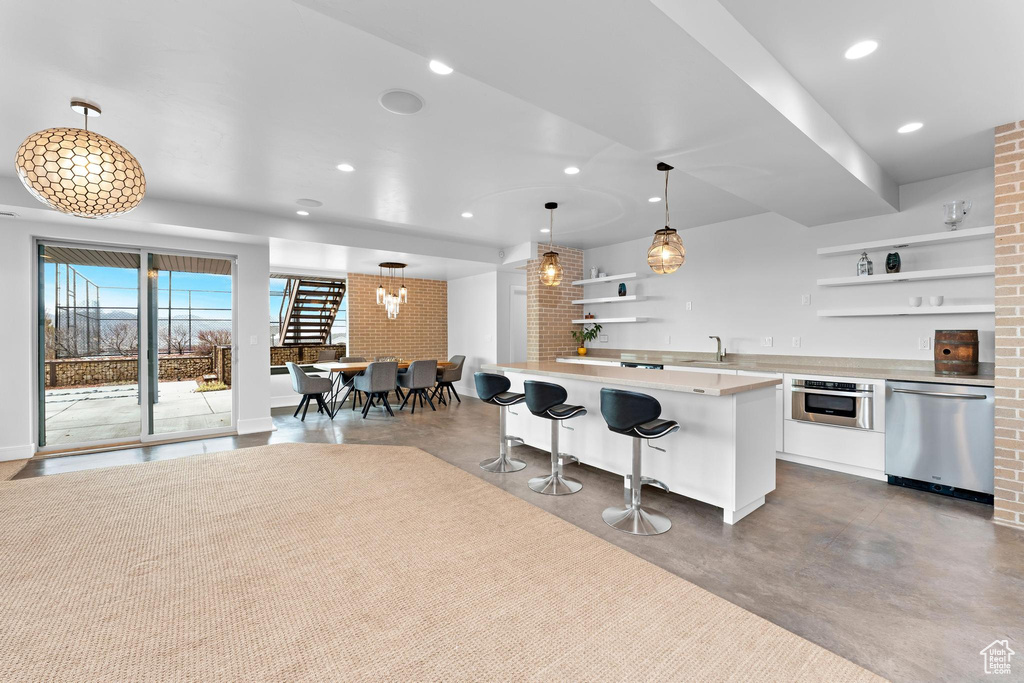 Kitchen with appliances with stainless steel finishes, open shelves, concrete flooring, light countertops, and recessed lighting