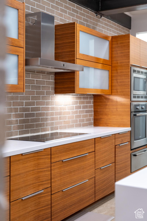 Kitchen featuring wall chimney exhaust hood, appliances with stainless steel finishes, a warming drawer, modern cabinets, and brown cabinetry