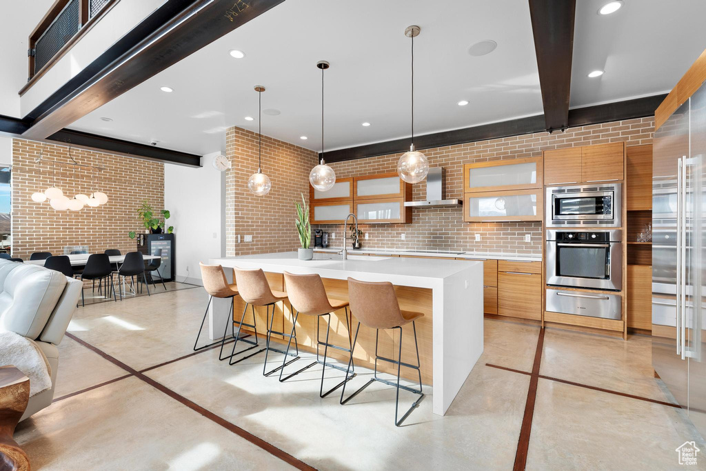 Kitchen with built in appliances, a warming drawer, modern cabinets, wall chimney exhaust hood, and light countertops