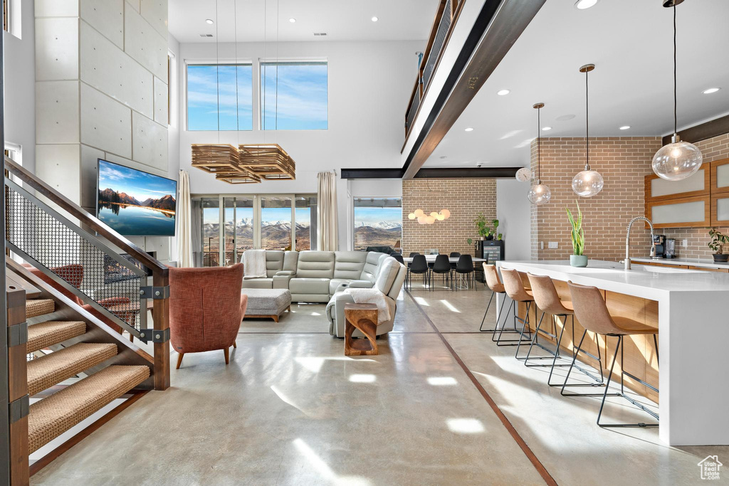 Living room featuring concrete floors, a high ceiling, recessed lighting, and stairway
