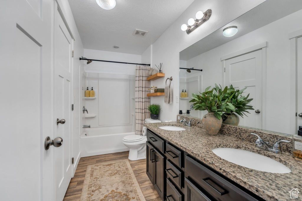 Full bath featuring double vanity, wood finished floors, and shower / tub combo with curtain