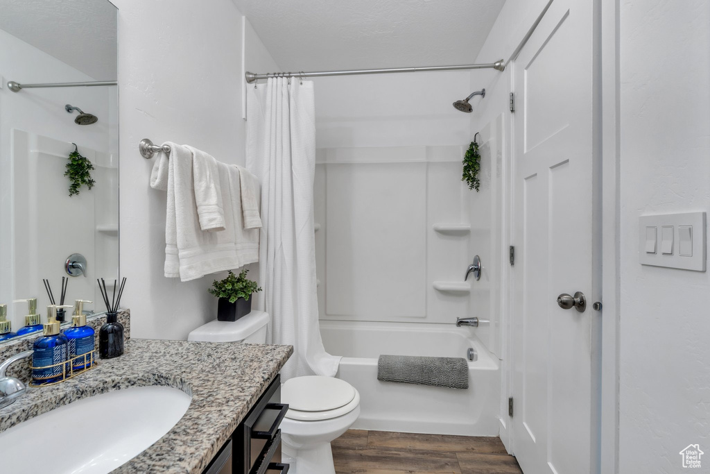 Full bath featuring vanity, shower / bathtub combination with curtain, and wood finished floors