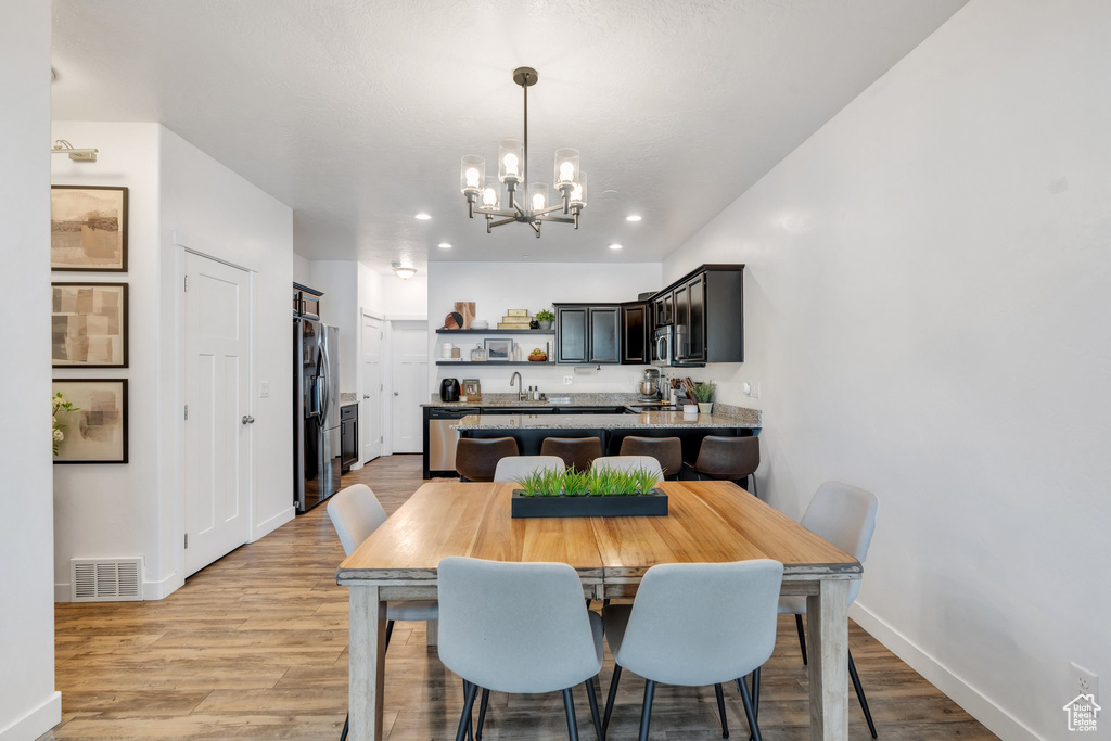 Dining area with a chandelier, light wood-style flooring, and recessed lighting