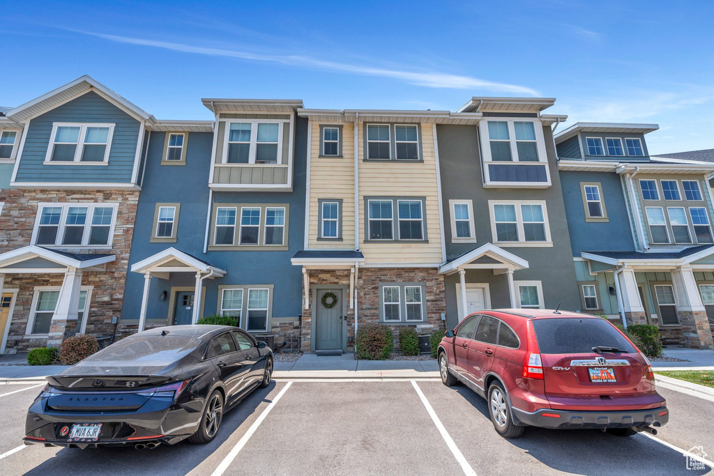 Multi unit property with stone siding, uncovered parking, and stucco siding