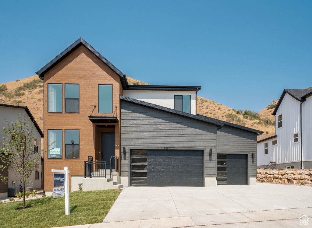 Contemporary house with concrete driveway, a garage, and a front lawn