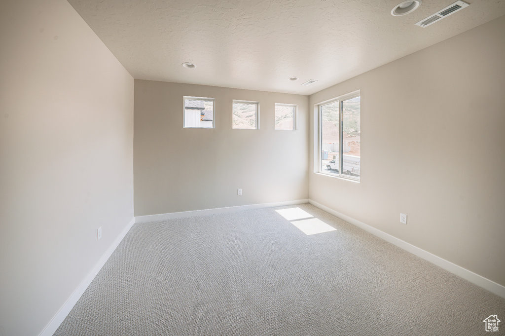 Carpeted empty room featuring healthy amount of natural light and recessed lighting