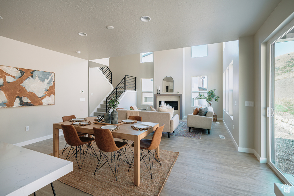 Dining room with stairway, a fireplace, light wood-style floors, recessed lighting, and a textured ceiling
