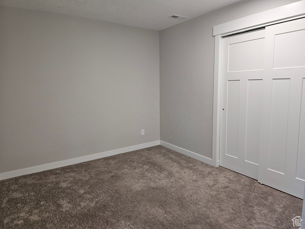 Unfurnished bedroom with carpet flooring, a closet, and a textured ceiling