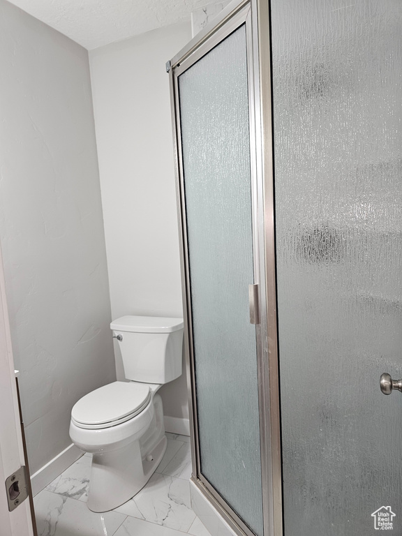 Full bathroom featuring a shower stall and marble look tiles