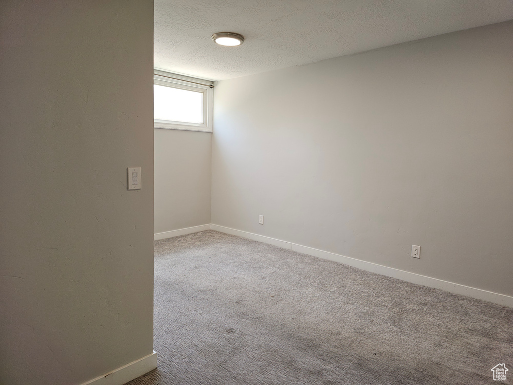 Empty room featuring carpet flooring and a textured ceiling