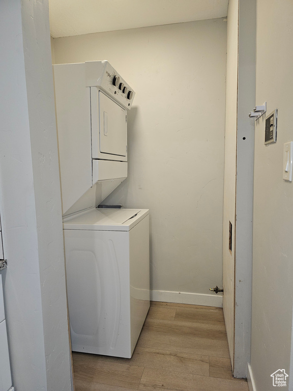 Laundry area featuring stacked washer and clothes dryer and light wood-type flooring