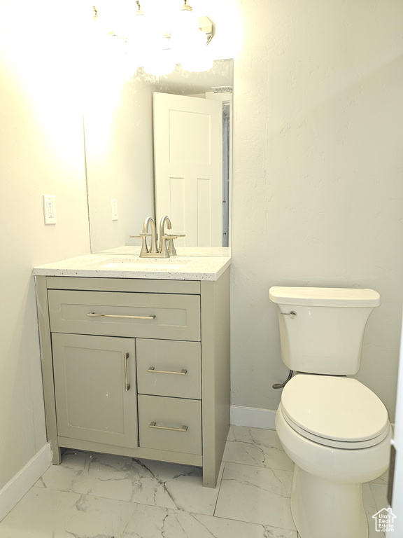 Half bath featuring marble finish flooring and vanity