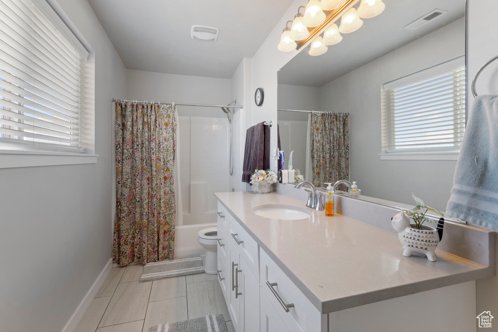 Bathroom featuring vanity, plenty of natural light, shower / bath combination with curtain, and tile patterned flooring