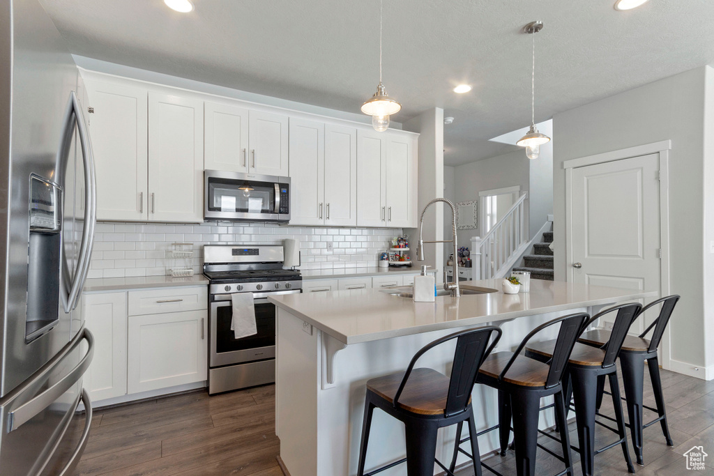 Kitchen featuring stainless steel appliances, backsplash, light countertops, dark wood-style flooring, and recessed lighting