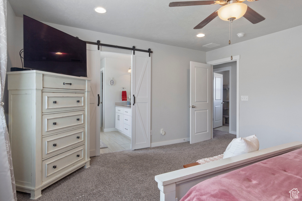 Bedroom featuring light colored carpet, recessed lighting, a barn door, ensuite bath, and ceiling fan