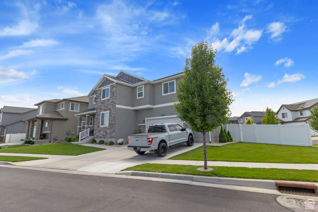 View of front facade featuring stone siding, a residential view, driveway, stucco siding, and a garage