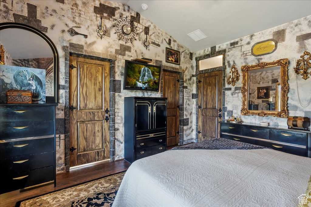 Bedroom with wood finished floors and lofted ceiling