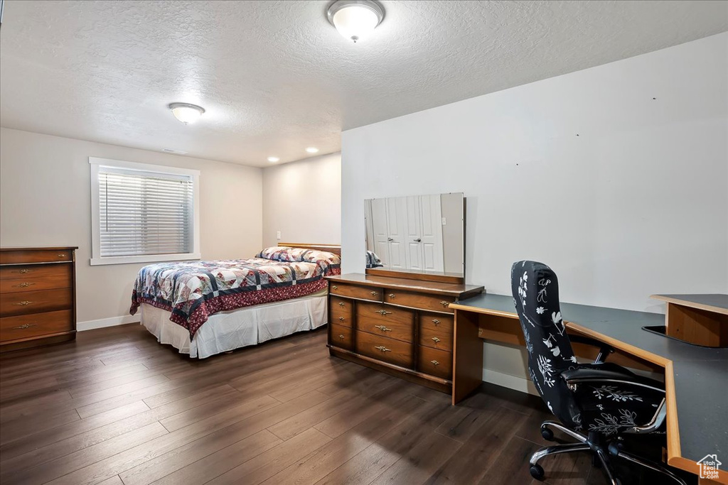 Bedroom featuring a textured ceiling, an office area, and dark wood-style flooring