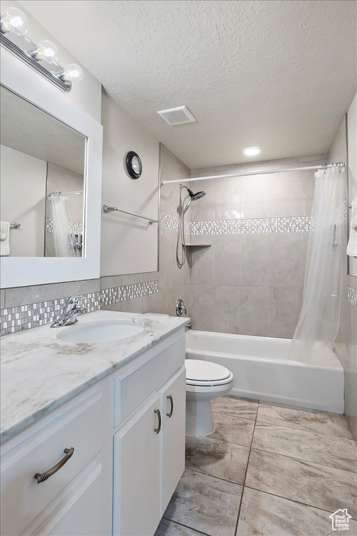 Full bathroom with vanity, shower / bathtub combination with curtain, a textured ceiling, and decorative backsplash