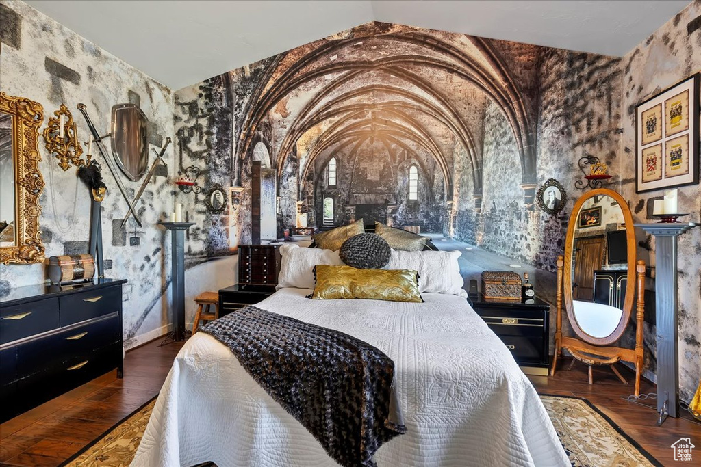 Bedroom featuring vaulted ceiling, wood finished floors, and wallpapered walls
