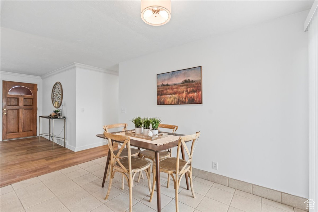 Dining area with light tile patterned floors and ornamental molding