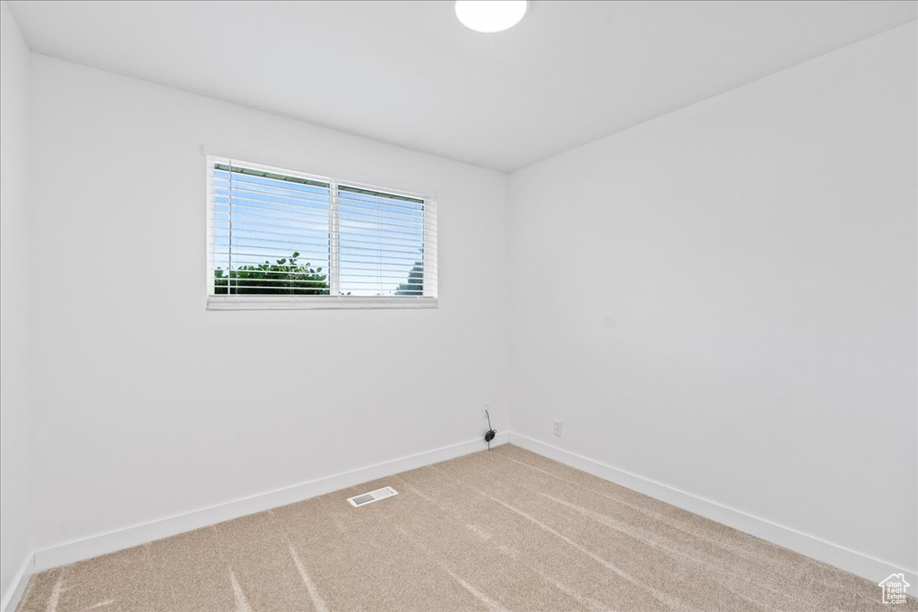 Carpeted spare room featuring baseboards