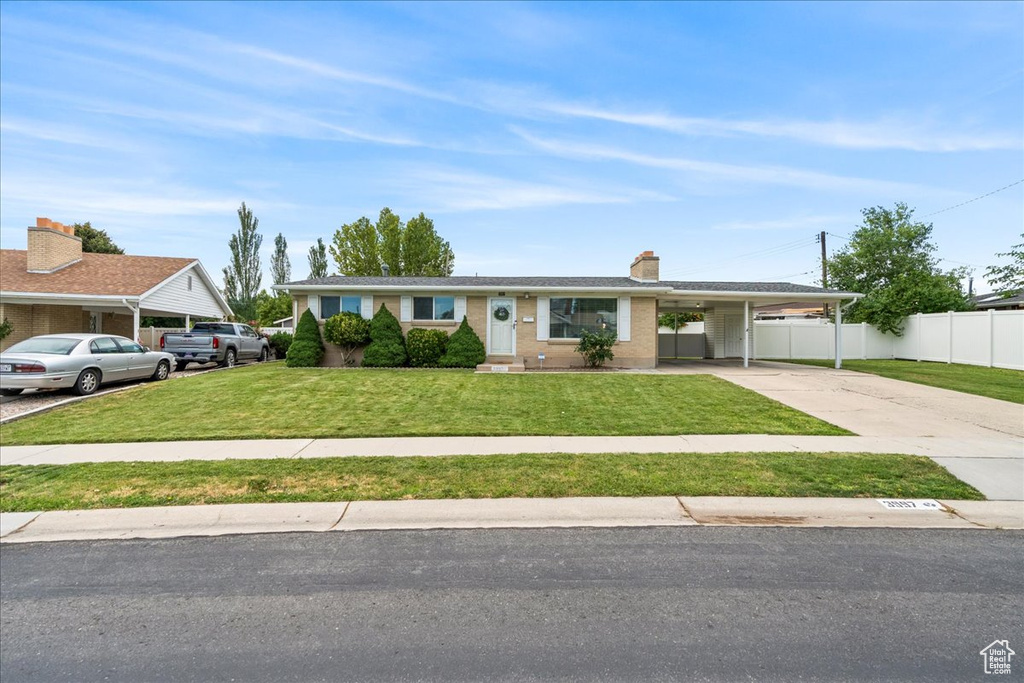 Single story home featuring concrete driveway, an attached carport, and a chimney