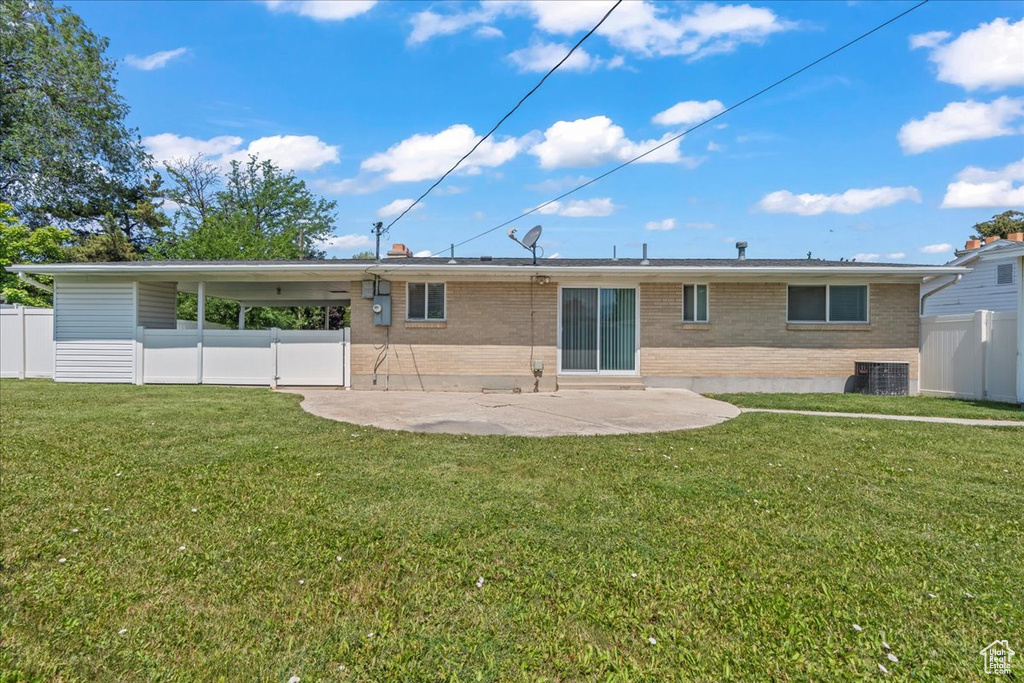 Rear view of property featuring brick siding, a patio area, and a carport