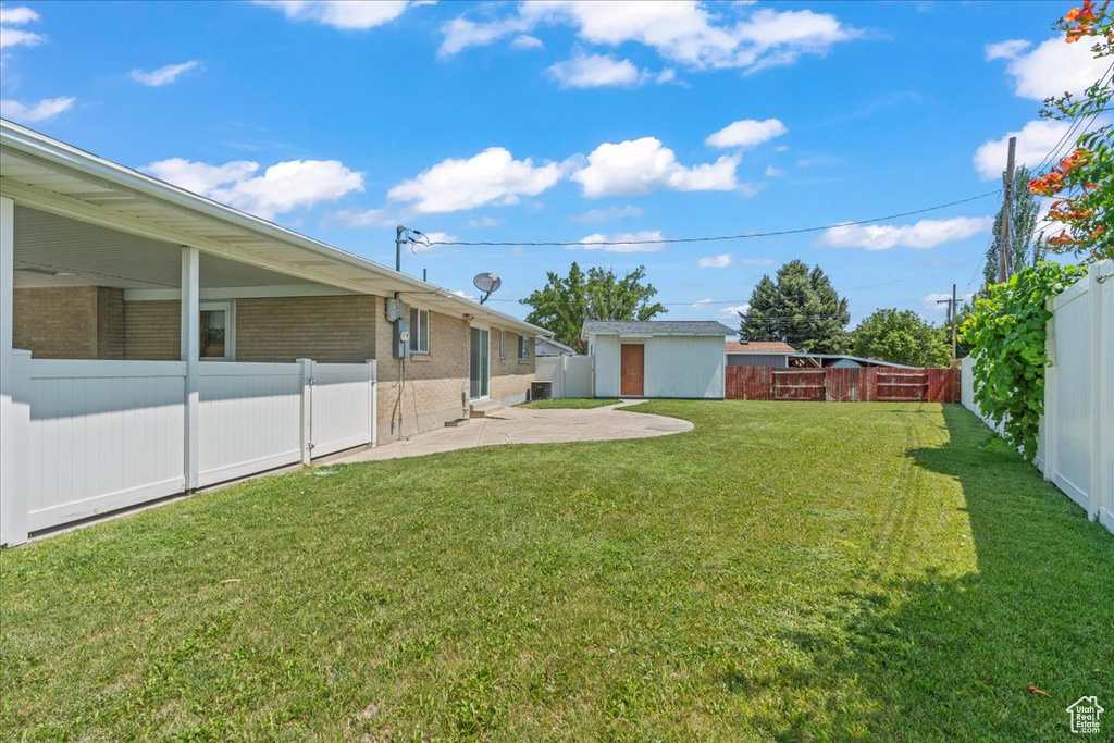 Fenced backyard featuring a patio area and a shed