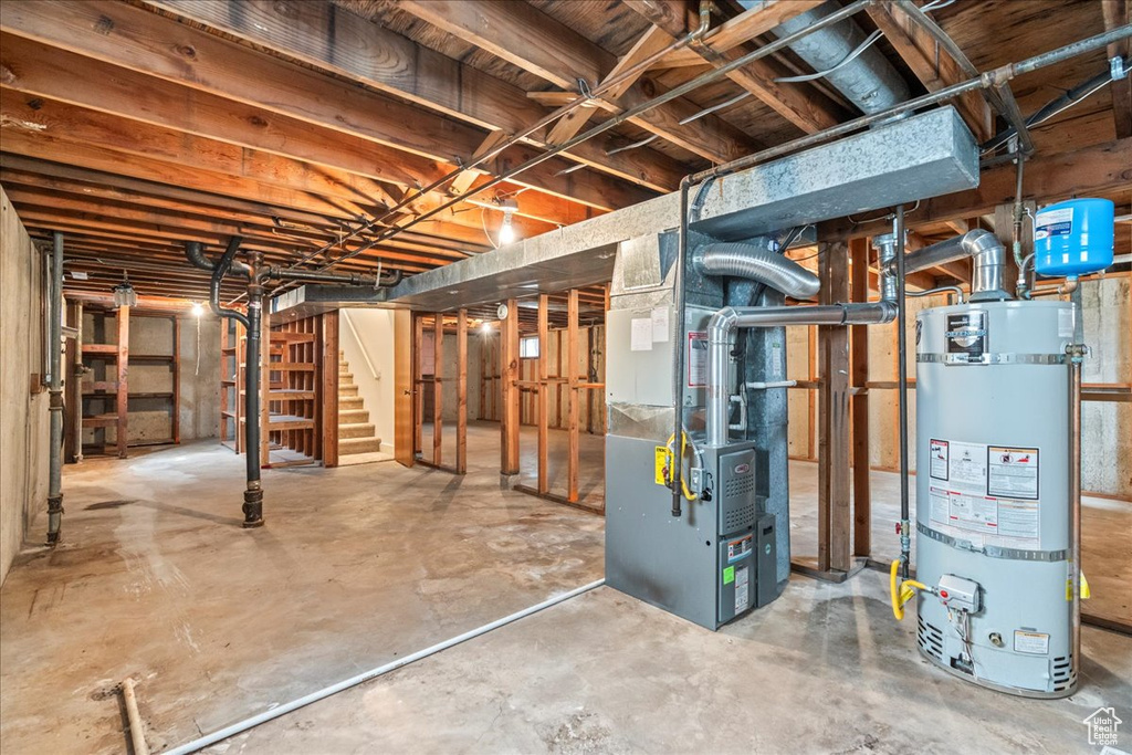 Unfinished basement with water heater, heating unit, and stairs