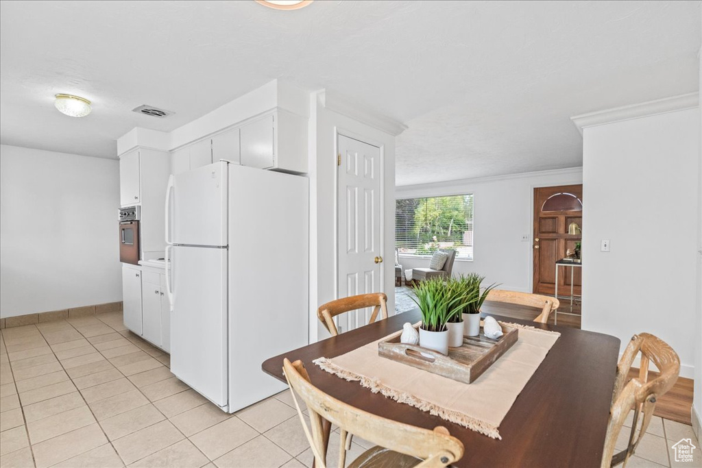 Dining room with light tile patterned floors and crown molding