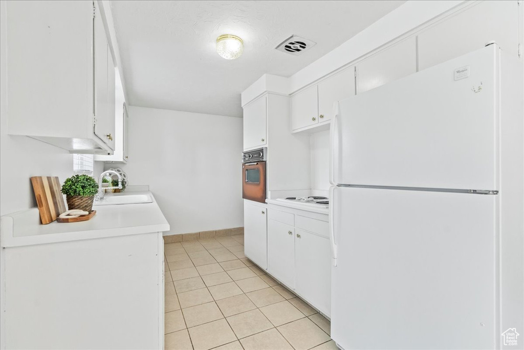 Kitchen featuring white appliances, light countertops, light tile patterned flooring, and white cabinetry