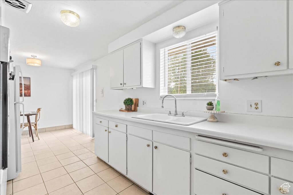 Kitchen featuring light tile patterned floors, light countertops, and white cabinetry
